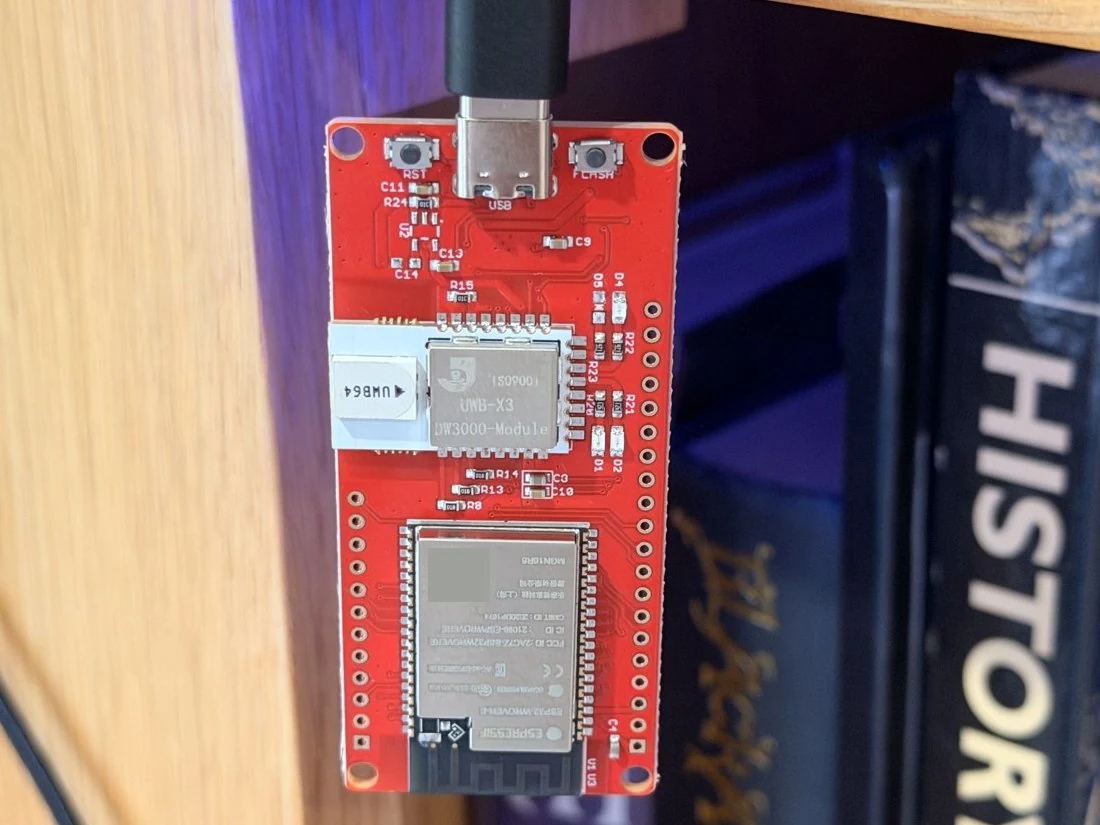 一块红色的 Makerfabs ESP32-WROVER 开发板,连接了 USB,可见其 UWB 模块和天线。