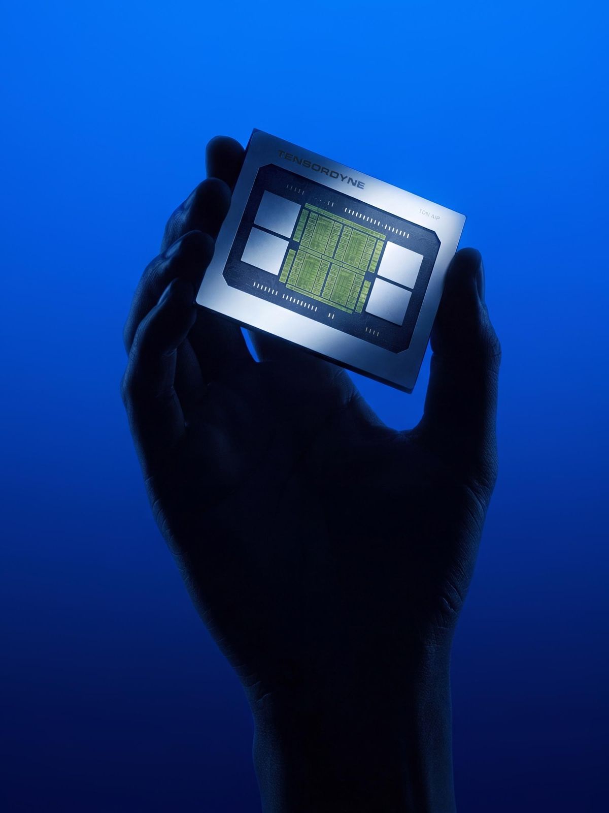 Silhouetted hand holding a glowing computer chip against a blue background