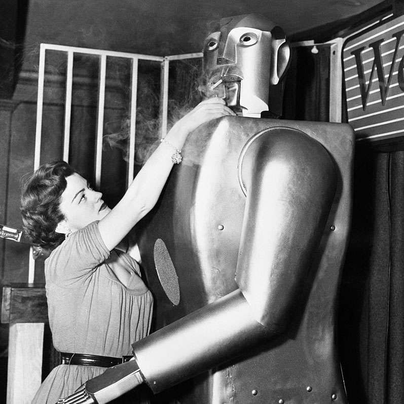 Jeanne Dowling reaches up to light a cigarette for Elektro, a seven foot robot built by Westinghouse.